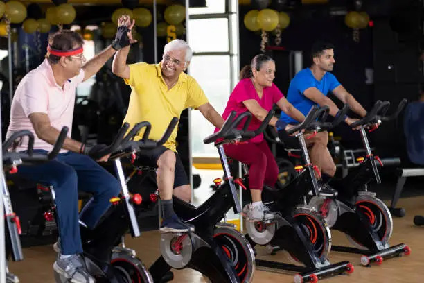 Men and woman in sportswear cycling at gym